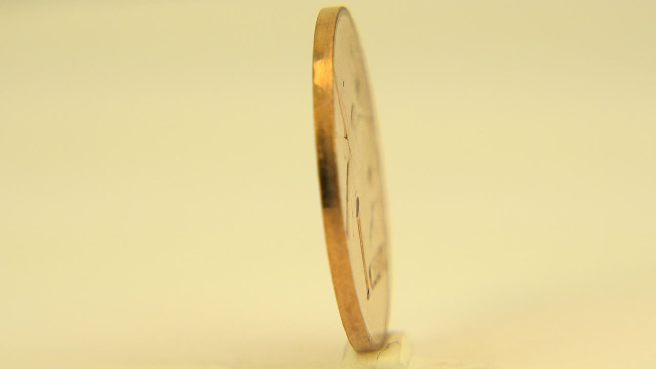 A Canadian penny stands nearly edge-on in warm light in Westminster, Colorado, with a soft pale background and no visible people.