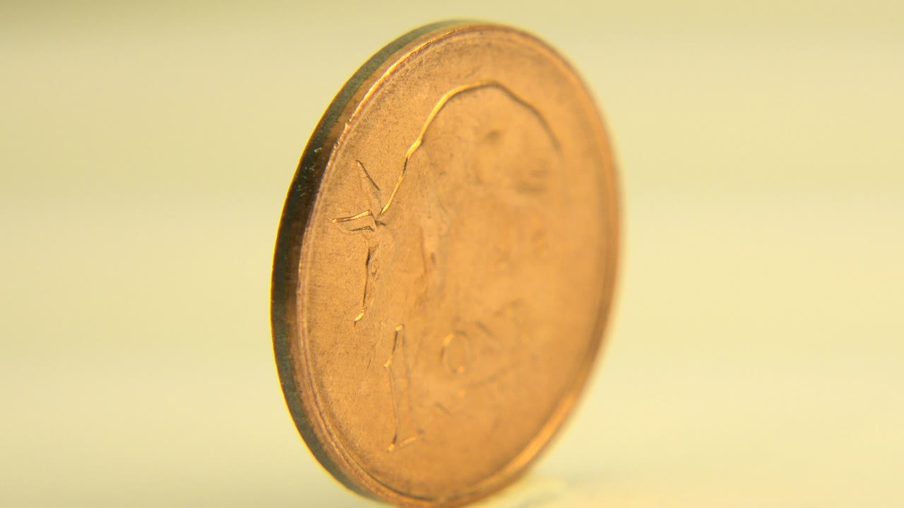 The coin remains upright in a close angled face view on the pale table, with shallow focus and no visible people in the Westminster, Colorado clip.