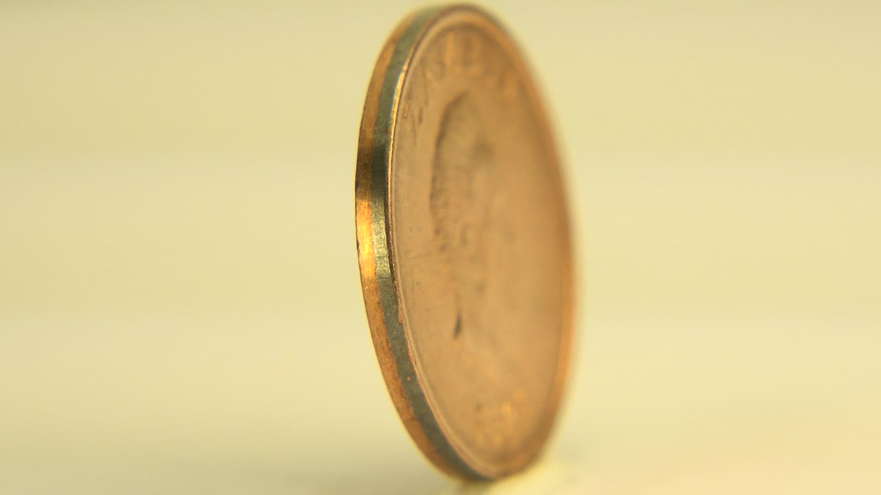 Partly turned gold-toned coin standing upright.