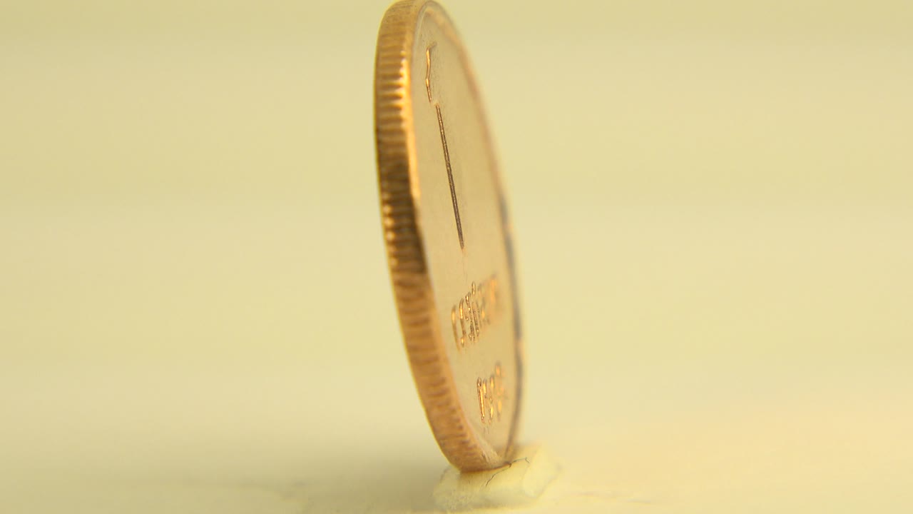 Coin standing upright with its reverse side partly visible.
