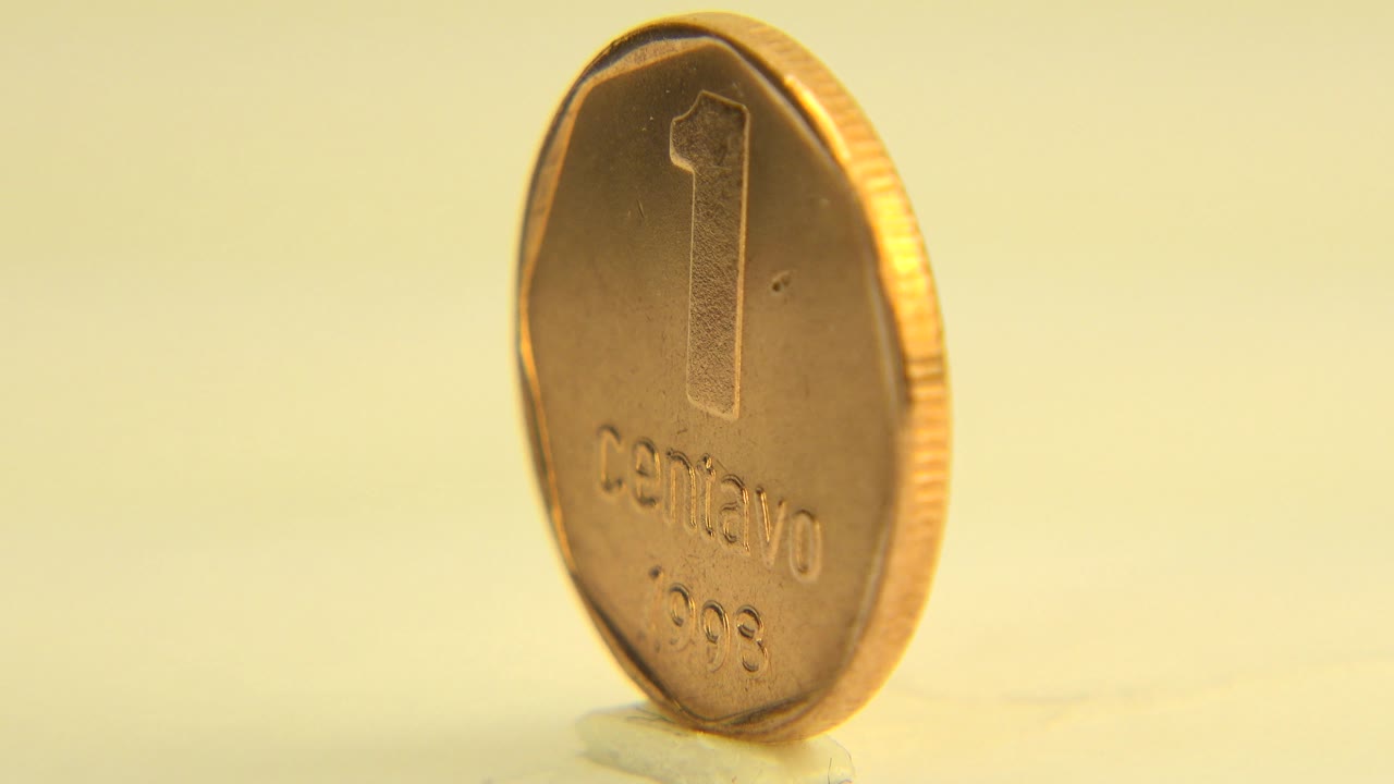 Centavo coin turned partly sideways on a pale surface.