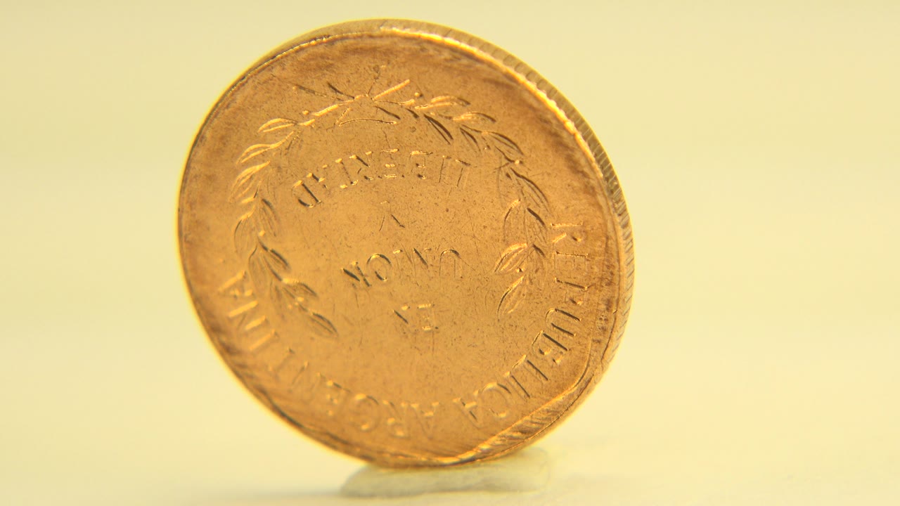 Golden penny tilted slightly with worn face visible.