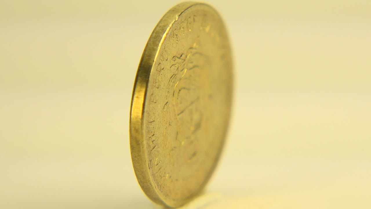 Upright golden coin in warm shallow focus in Westminster, Colorado 2015 footage, with its edge prominent and no visible people.