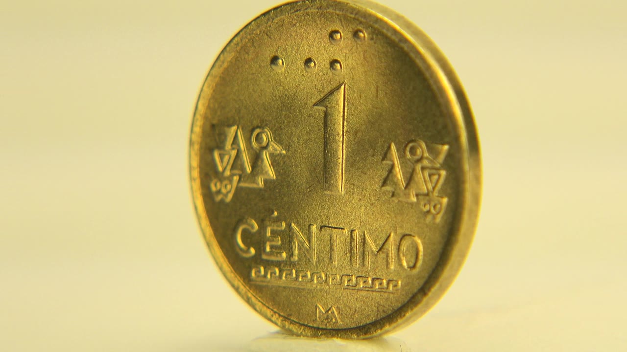 The coin remains nearly face-on in the Westminster, Colorado clip, with the one centimo text and raised symbols visible in soft focus and no visible people.