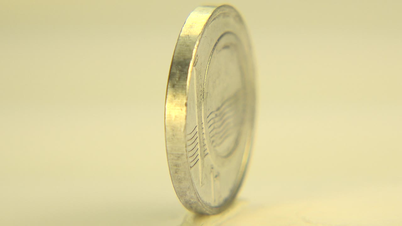 Coin partly turned with its face beginning to show.