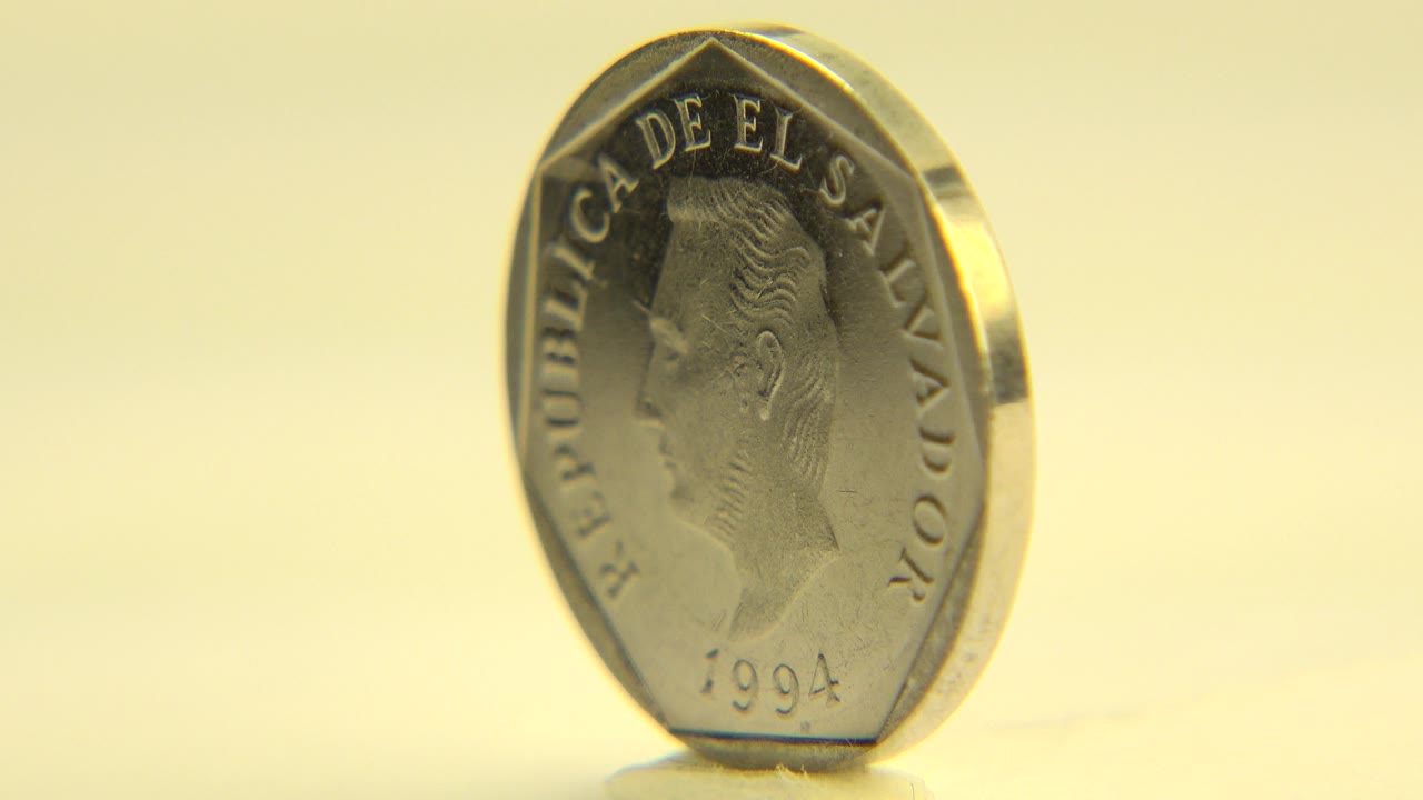 Gold-toned coin upright on a pale surface in Westminster, Colorado 2015 footage, showing a portrait side with no visible people.