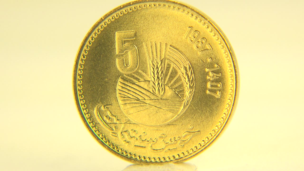 The coin remains upright and face-on in warm light, with the 5 marking and circular border visible on the pale tabletop in Westminster, Colorado, and no visible people.