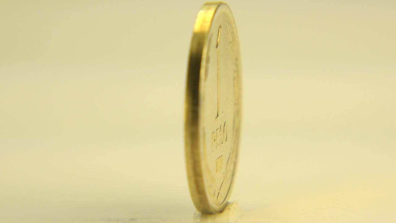 The coin remains mostly edge-on with a thin reflective rim and a softly lit pale background in Westminster, Colorado, with no visible people.