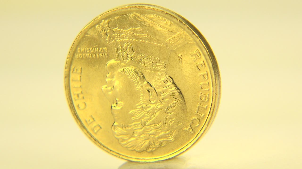 The coin remains upright and mostly face-on, showing the embossed portrait and rim lettering against a pale yellow background in Westminster, Colorado, with no visible people.