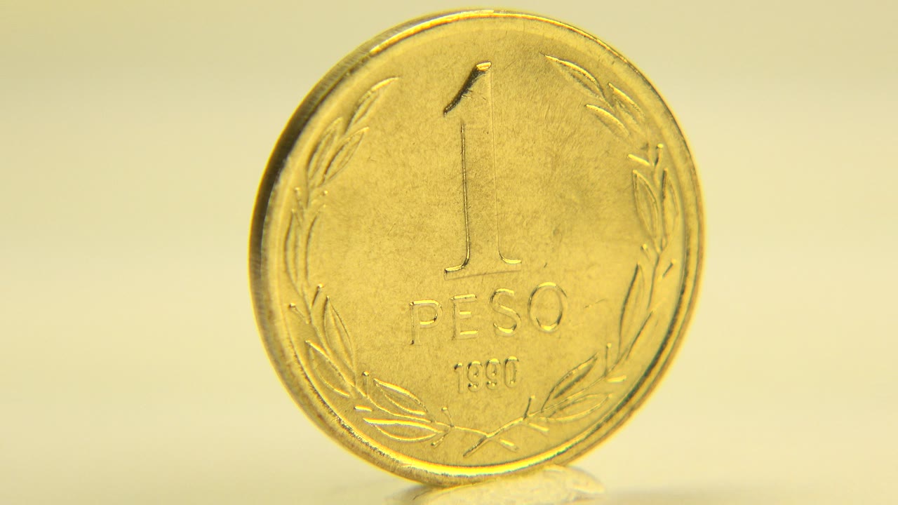 Front view of a gold-toned 1 peso coin on a pale surface.