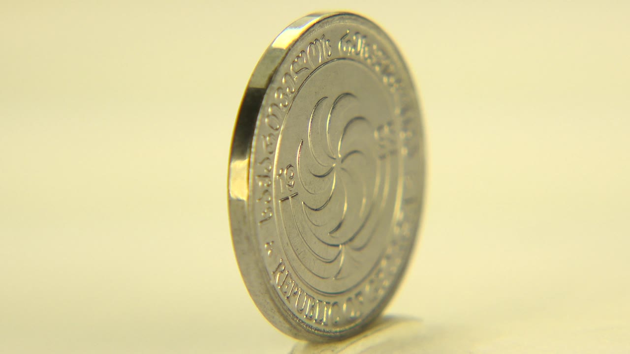 Silver coin tilted toward camera with face markings visible.
