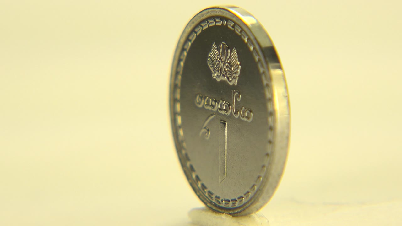 Silver coin turned partly sideways on a tabletop.