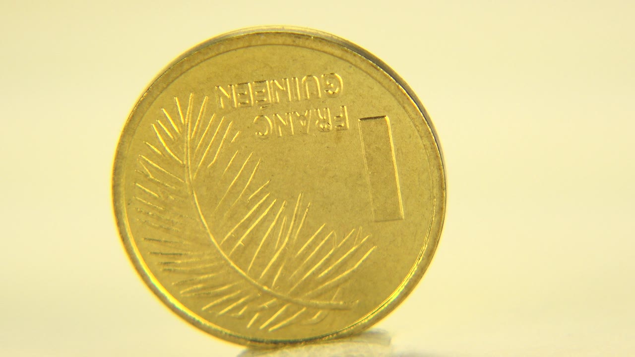 Gold-colored coin shown nearly face-on on a pale tabletop in Westminster, Colorado, with warm yellow light and no visible people.
