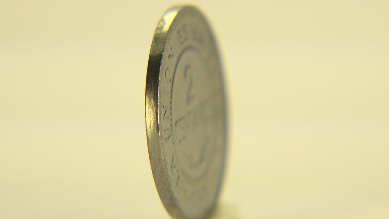 Close-up of an upright coin in Westminster, Colorado, seen mostly edge-on with soft focus, warm yellow light, and no visible people.