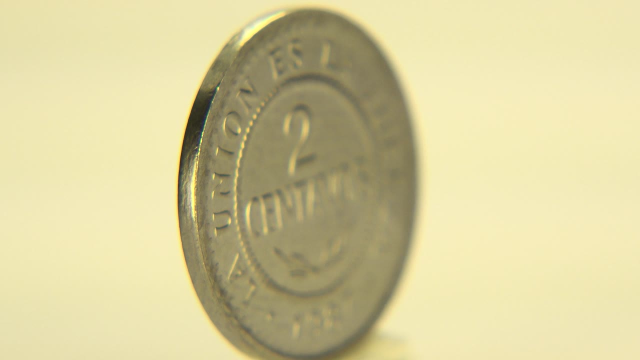Coin face becomes more visible, showing 2 centavos lettering.