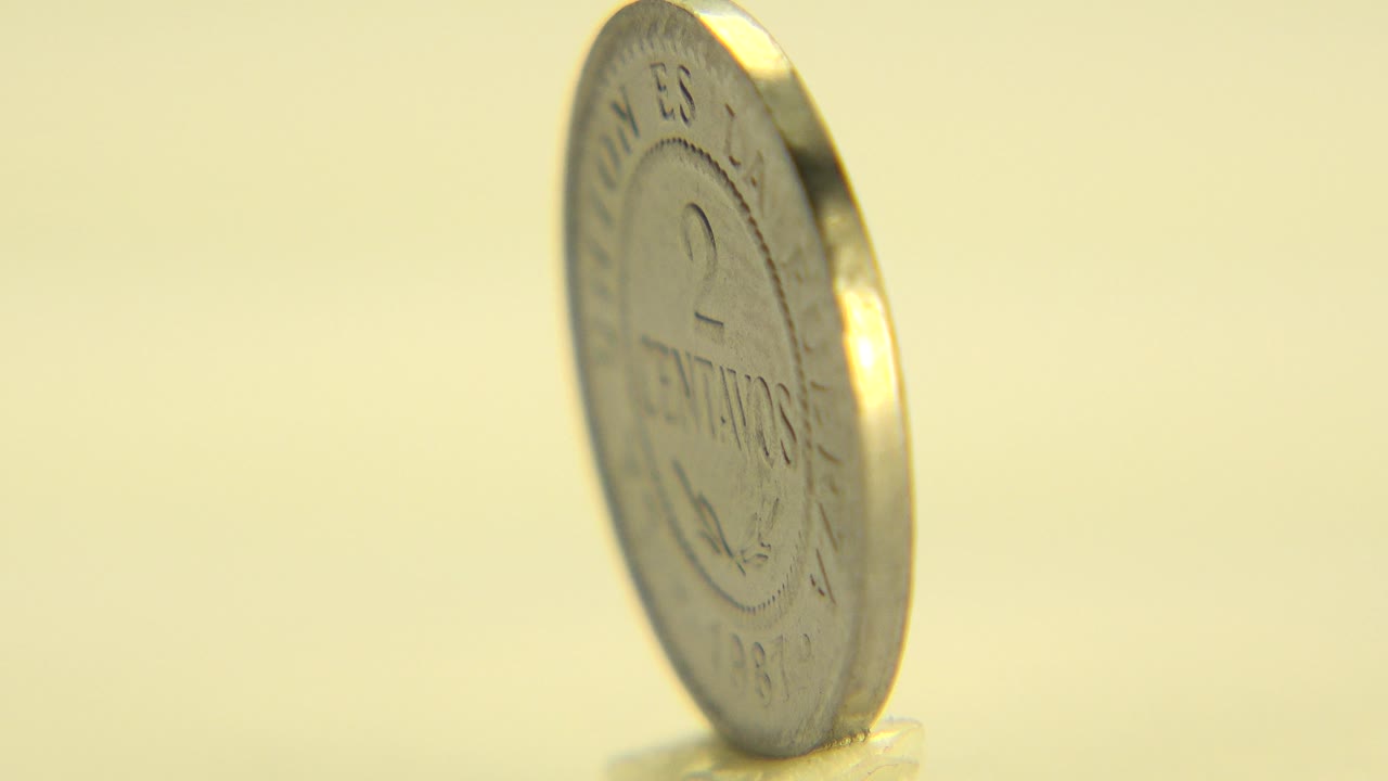 Bolivian coin standing on edge on a pale reflective surface.
