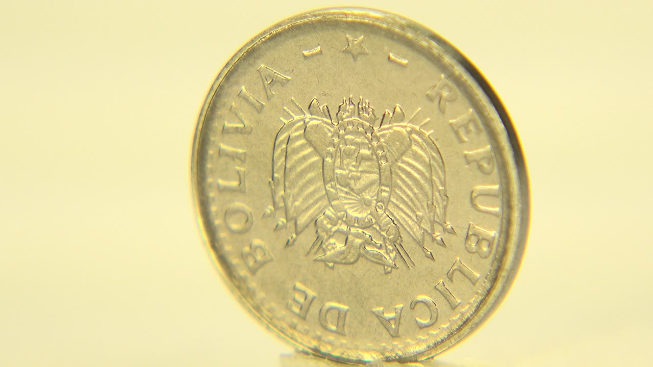 The coin stays nearly front-on in Westminster, Colorado, with the crest, circular rim, and worn gold surface visible against a warm background, with no visible people.