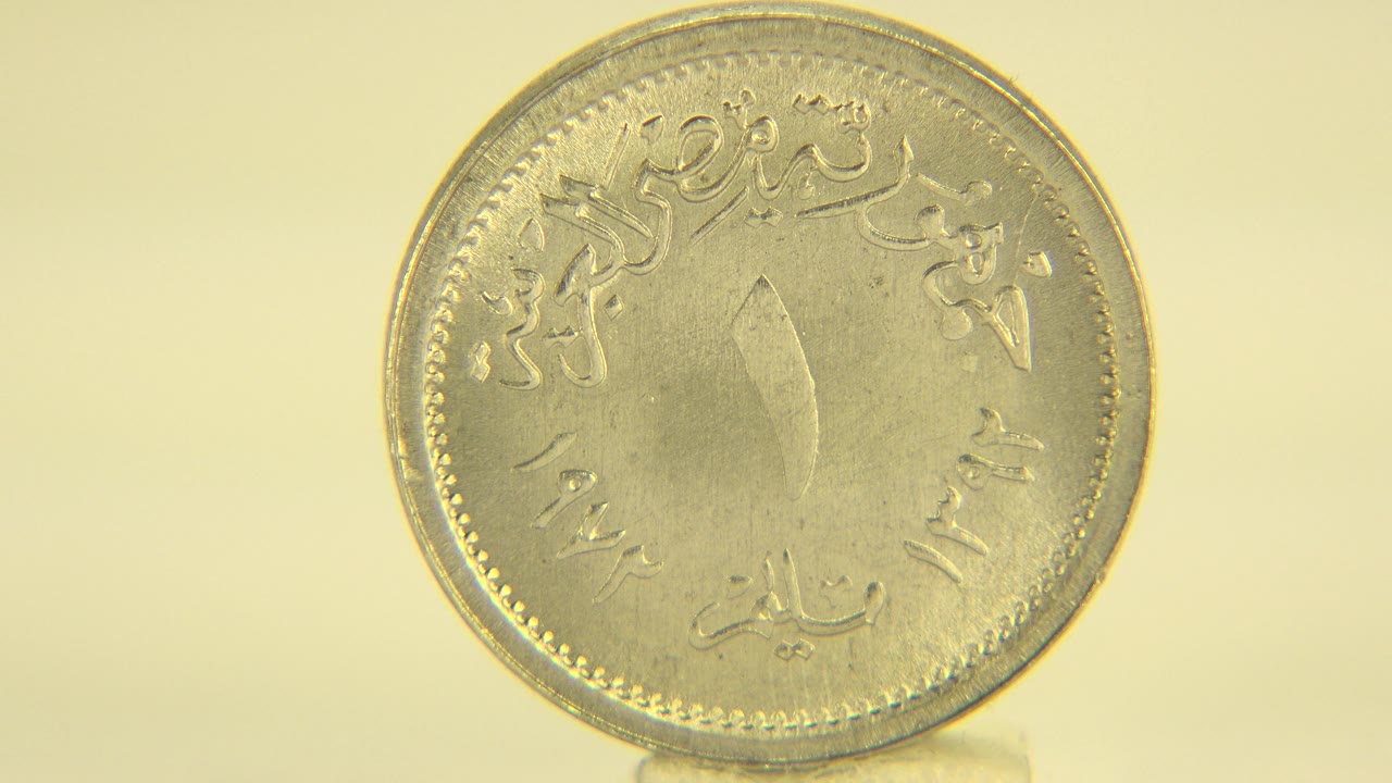 A silver-colored coin is shown nearly face-on on a pale yellow surface in the Westminster, Colorado clip, with no visible people.