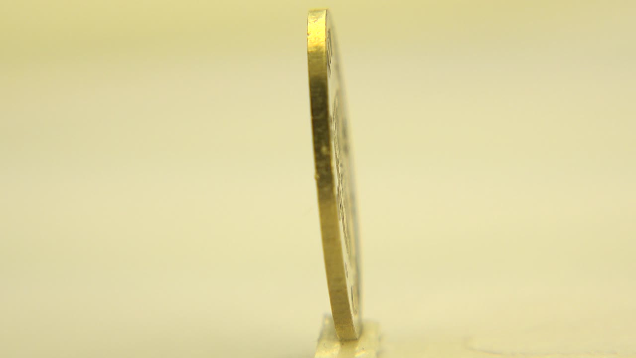 Thin coin standing on edge on a pale tabletop