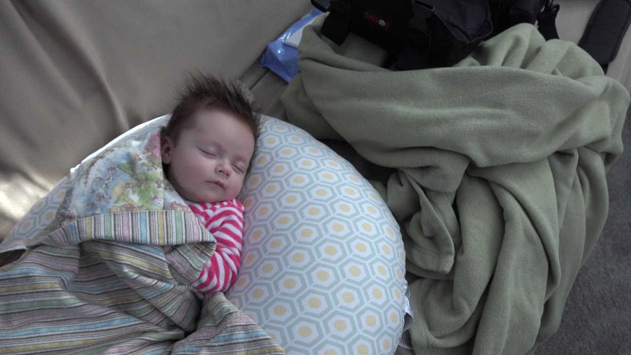 Wider view of a sleeping baby wrapped in bedding.