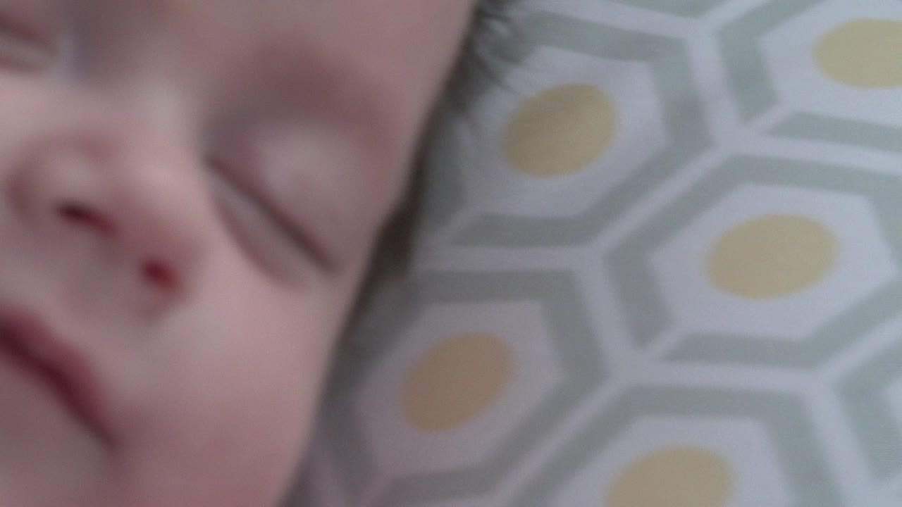 At 0:01, the baby's closed eyes and nose sit near the left side of the frame while the geometric blanket pattern fills the right side in Westminster, Colorado.