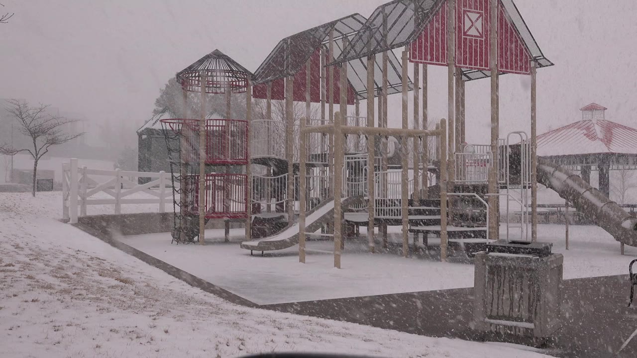 At 0:01, the empty Westminster, Colorado playground remains centered as falling snow partially veils the gazebo and bare trees behind it.