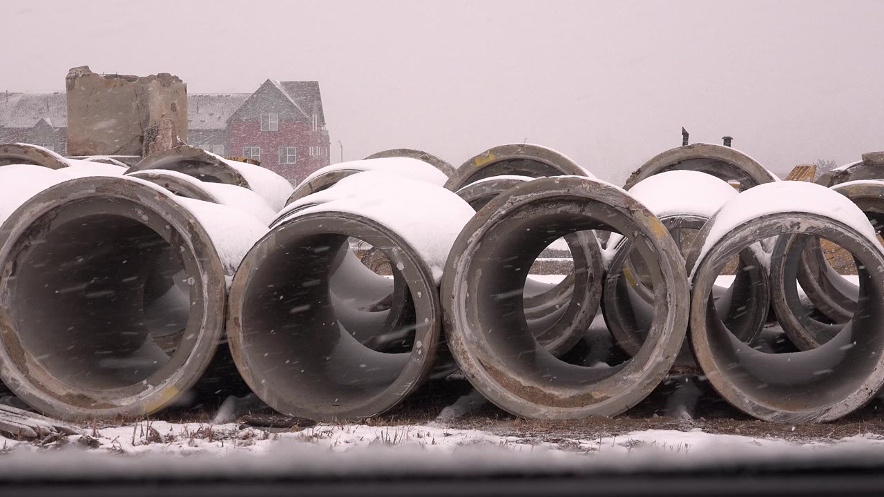 Rows of round concrete tubes sit under snow in Westminster, Colorado, with a pale overcast sky and no visible people.