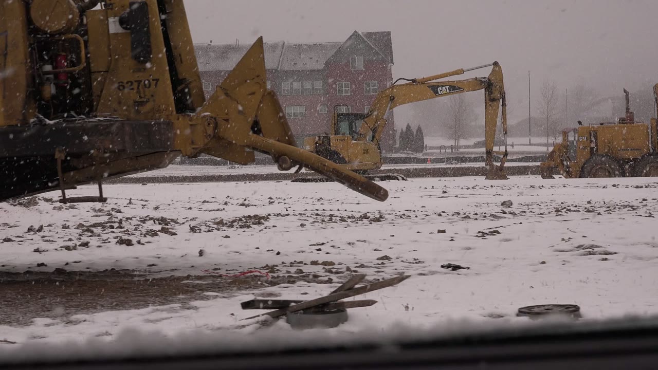 Yellow construction machinery beside a snowy work site.