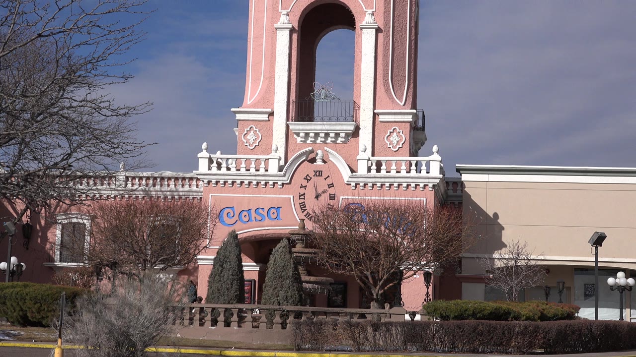 Wide view of a pink castle-like facade with Casa signage and bare trees.