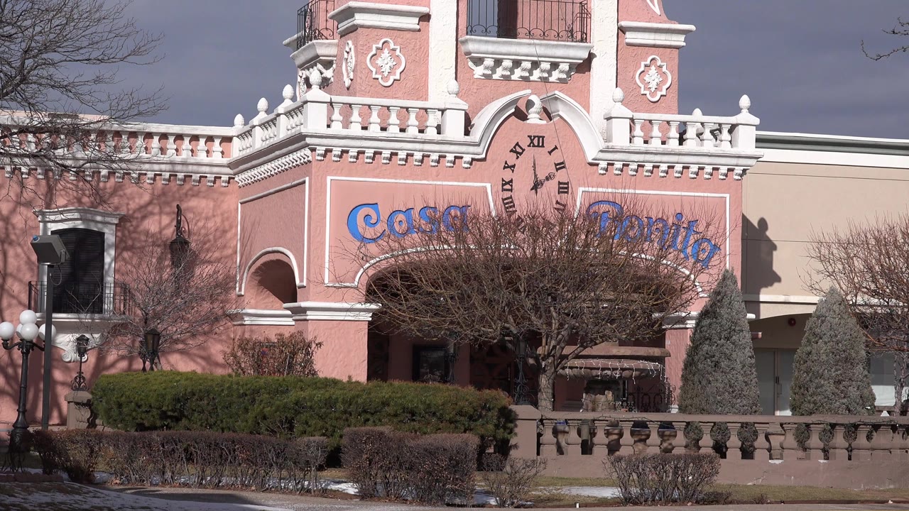 Pink Casa Bonita facade with shrubs and leafless trees.