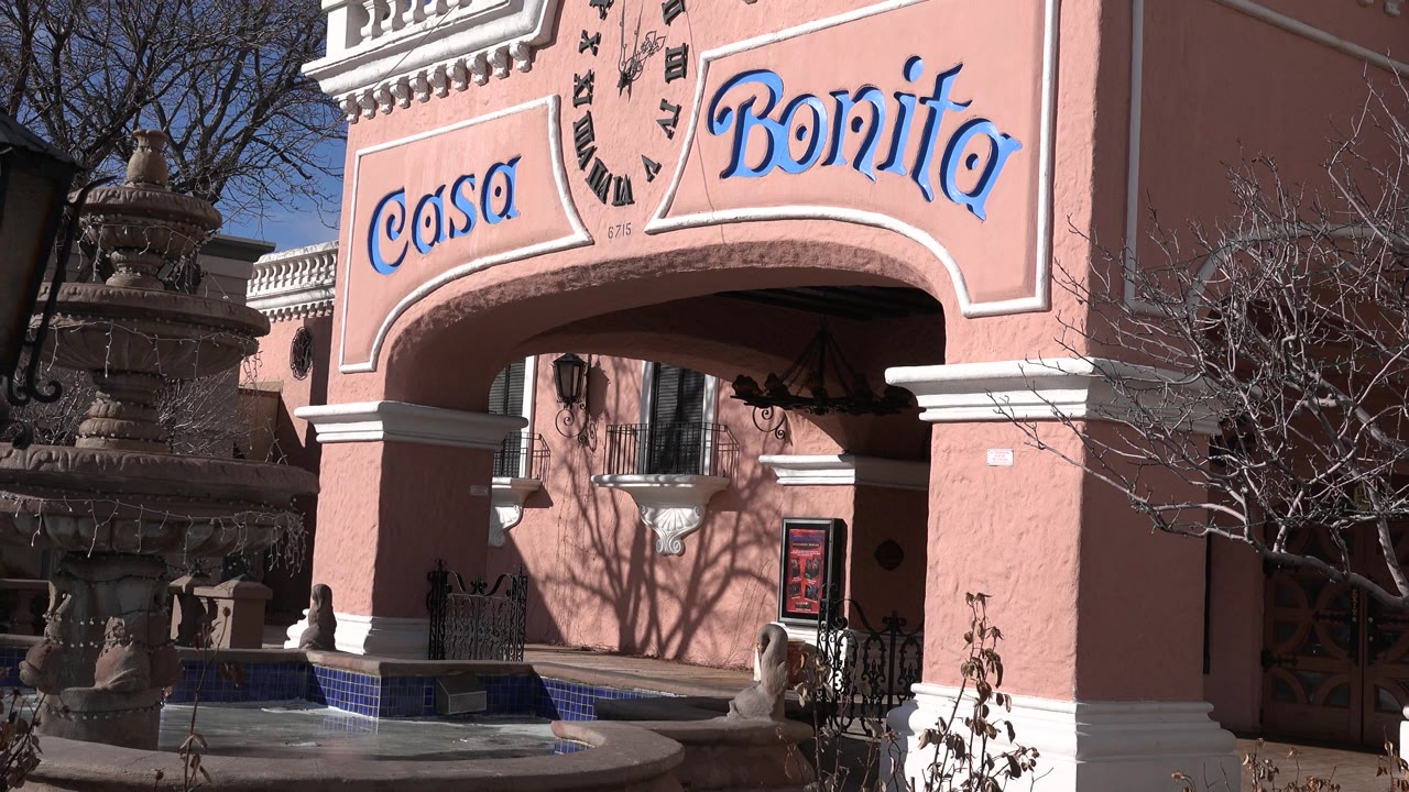 Denver exterior view moves tighter on the Casa Bonita sign above the arched entrance, with the fountain still partly visible at left and no visible people.