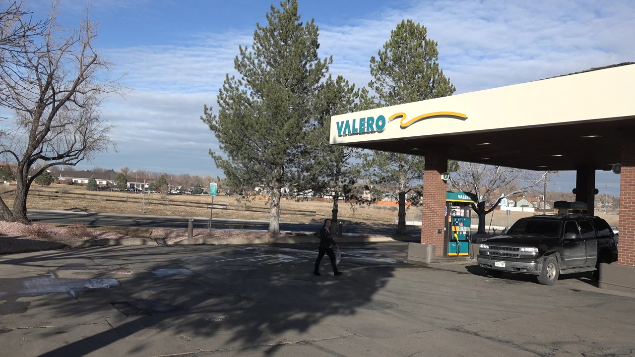 Dark SUV parked at a gas pump beneath a Valero canopy.