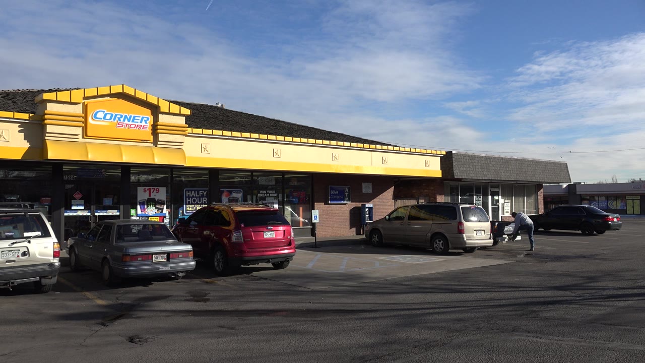 Yellow convenience store facade with parked vehicles and open sky.