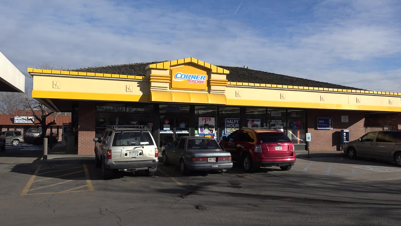 Denver storefront remains centered with parked vehicles lined up in front, window posters visible, and no visible people in the parking area at 0:01.