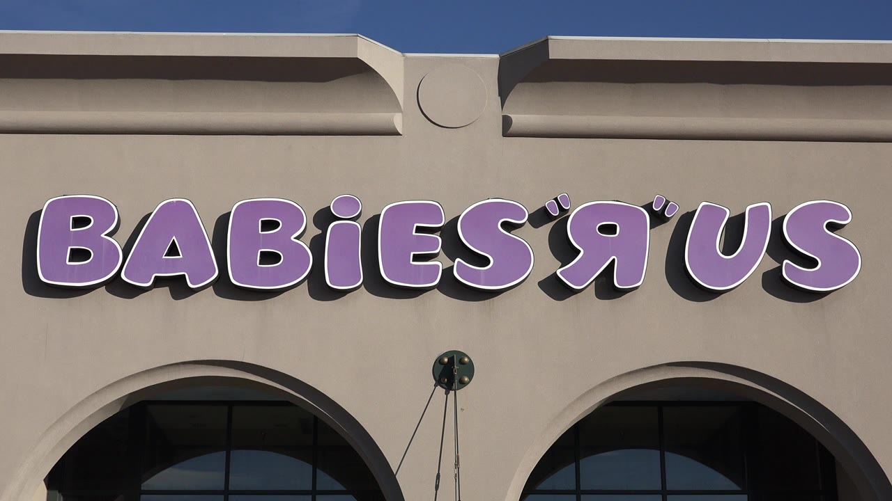 Tight view of Babies R Us sign on beige storefront facade.
