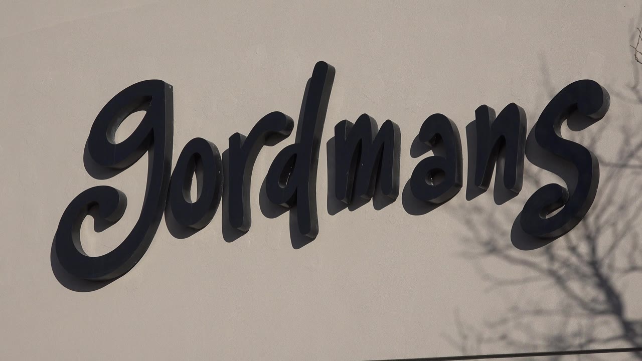 Close view of black Gordmans letters on a beige wall.