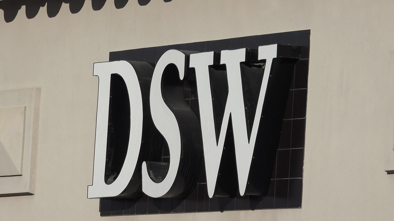 The Denver storefront sign remains tightly framed, with white letters casting dark shadows on a black backing and no visible people.