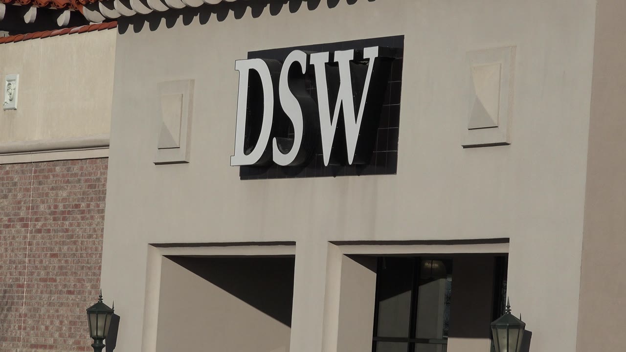 Denver storefront sign remains tight in frame, with the DSW letters above recessed window bays, partial brickwork, roof trim, and no visible people.