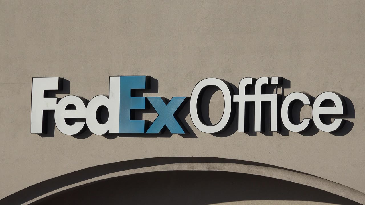 Close view of a FedEx Office sign on a beige facade.