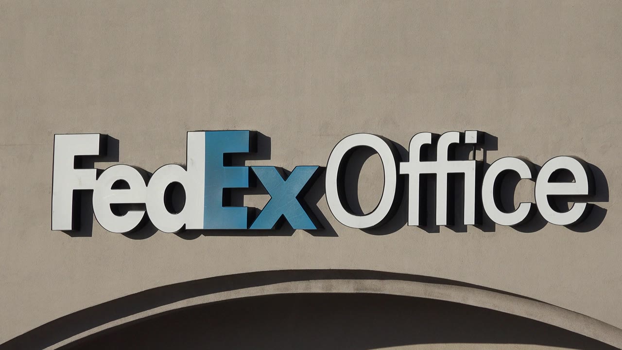 Close Denver view of the raised FedEx Office sign mounted above an arched beige storefront facade, with no visible people.