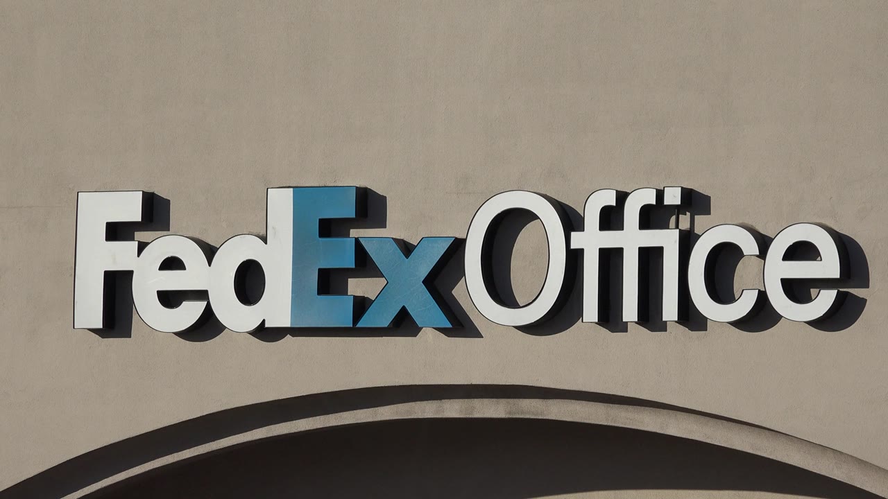 The FedEx Office lettering fills the upper frame in Denver, with blue and white raised letters casting shadows on the beige wall and no visible people.
