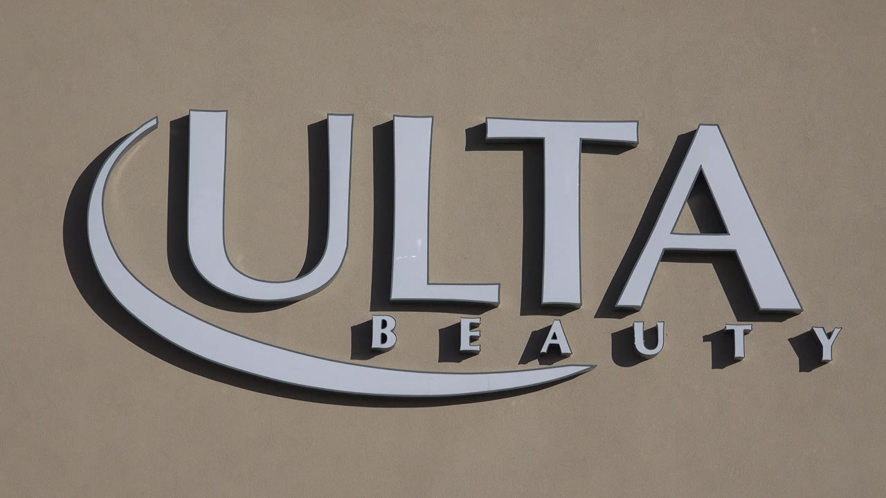 Centered Denver view of the Ulta Beauty sign mounted high on a tan strip mall facade, with strong sun and no visible people.
