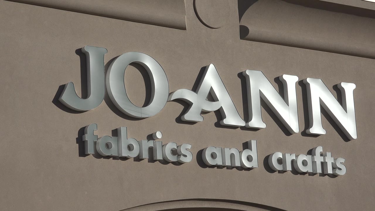 Second tight view of the Denver Joann sign, with the letters centered higher on the stucco wall and no visible people.