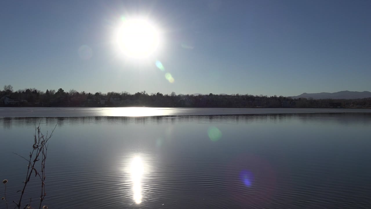 High sun over lake with shimmering reflection near the foreground.