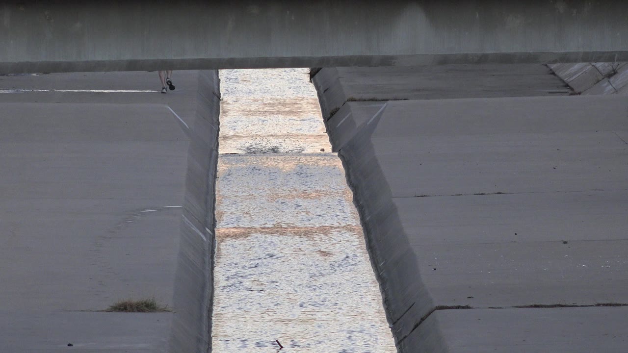 Second frame shows the Westminster concrete channel with the bright water strip slightly shifted in texture, sloped walls on both sides, and no visible people.