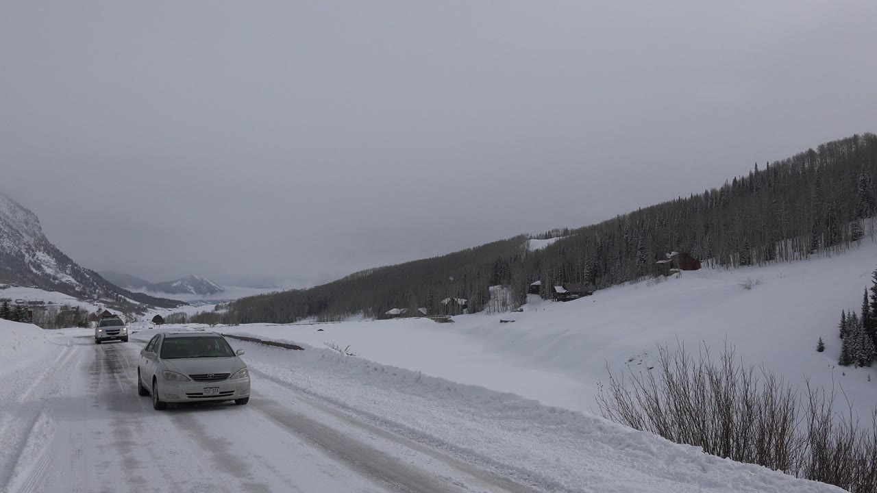 Light-colored car on a snowy mountain road