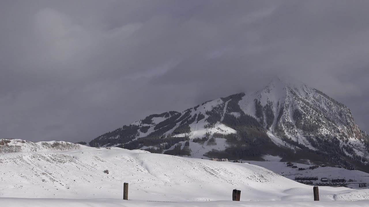 Snowy open terrain with a mountain and overcast sky