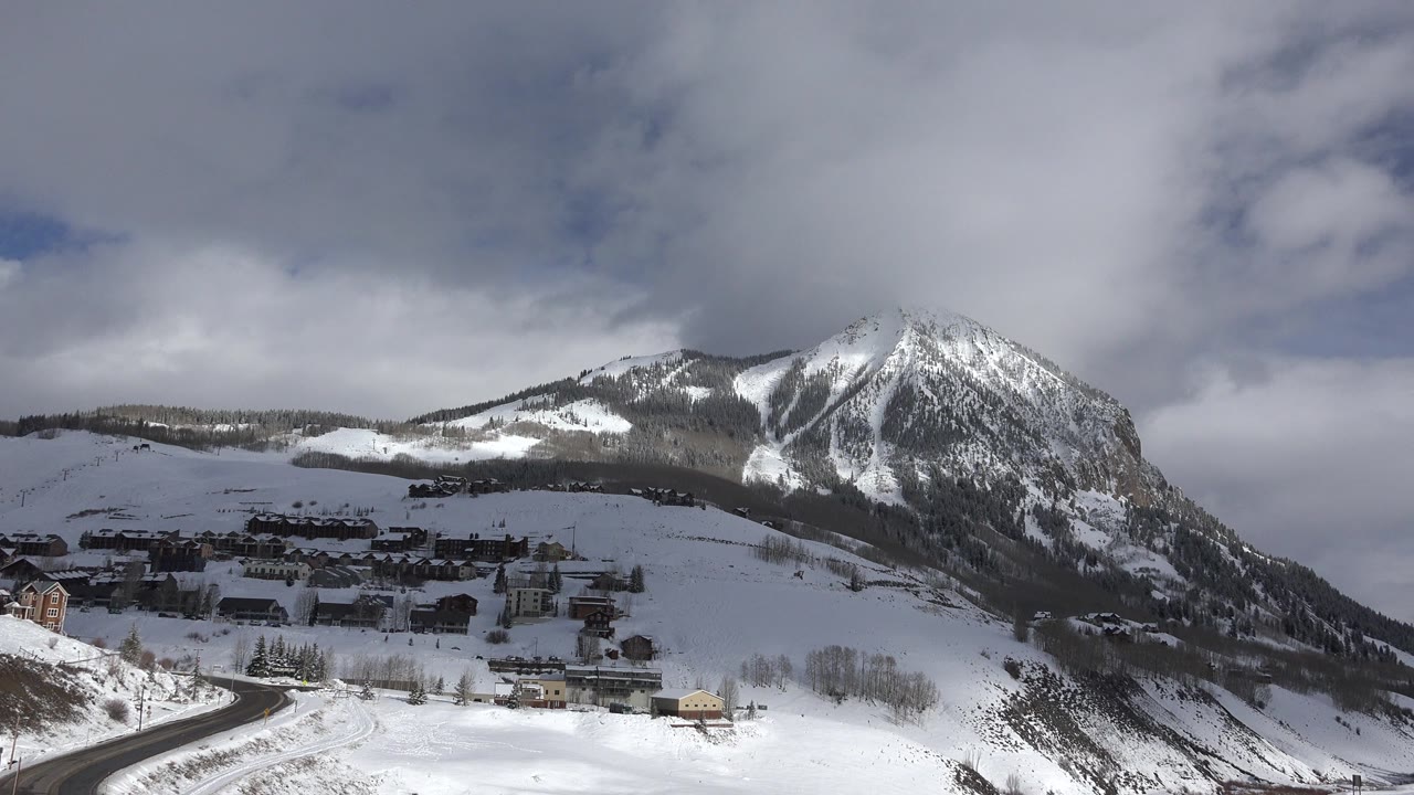 Snowy mountain town view with winding road and cloudy sky