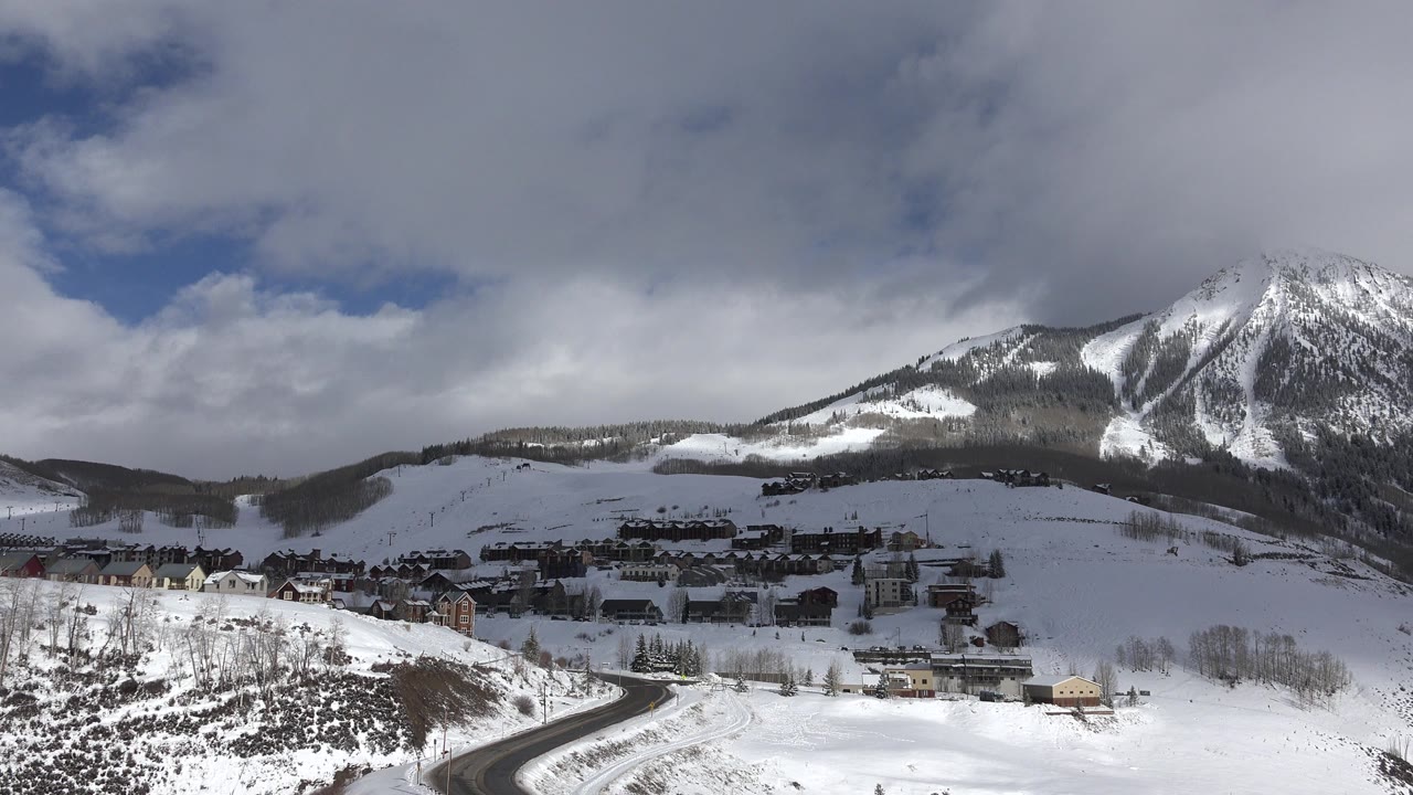 Snowy mountain town below a clouded peak