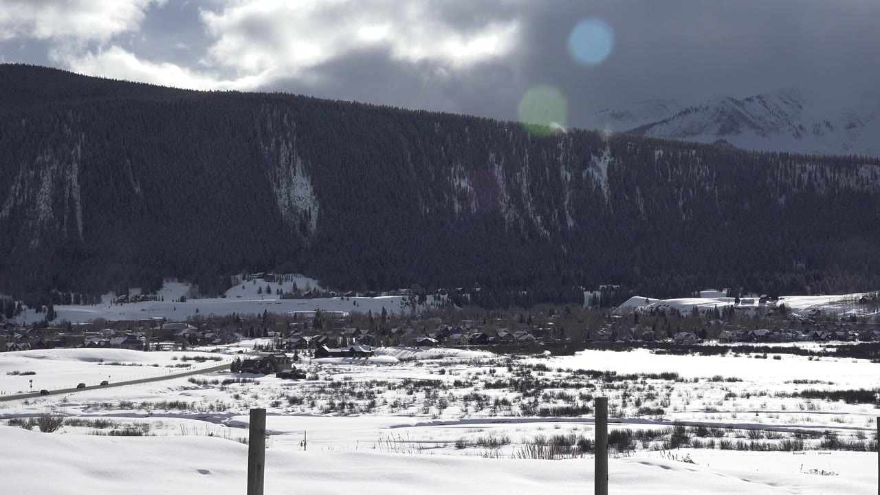 Fence posts in snowy valley with mountains behind